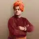 A colorized portrait of Swami Vivekananda, a renowned Indian spiritual leader, wearing an orange turban and maroon robe, with arms crossed wealthy tamilan