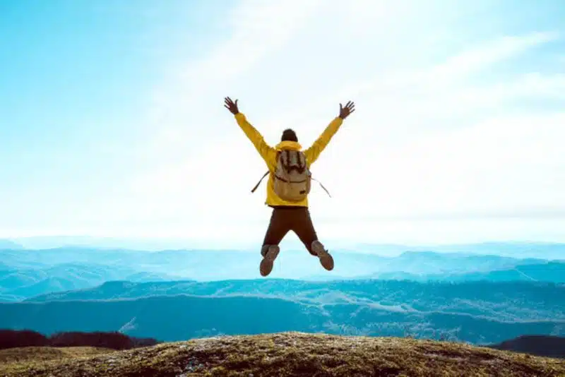 man jumping in top of the mountain blue shade latest quotes in tamil enjoy the life moments.